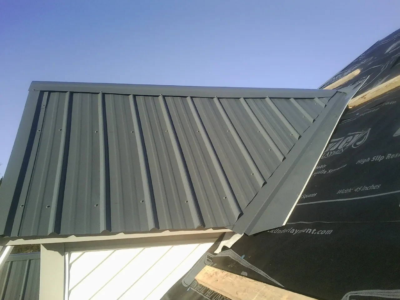 Gray metal roof panels going on over a garage gable in Halstead