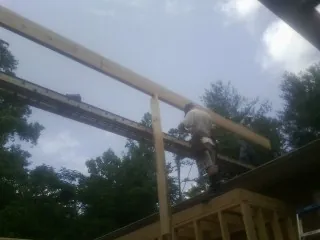 Carpenter setting a ridge beam over a new addition frame — Ice Dam Removal by Roofing Brothers in Halstead