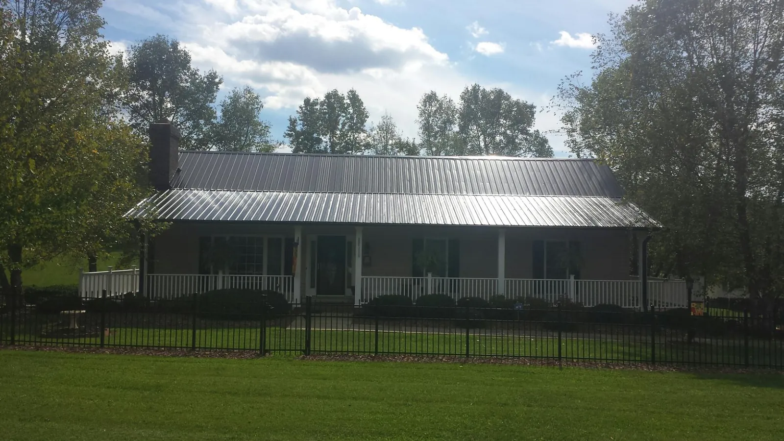 Gray metal roof on a brick ranch with a full width front porch — Gutter Guard Installation work by our crew in Halstead