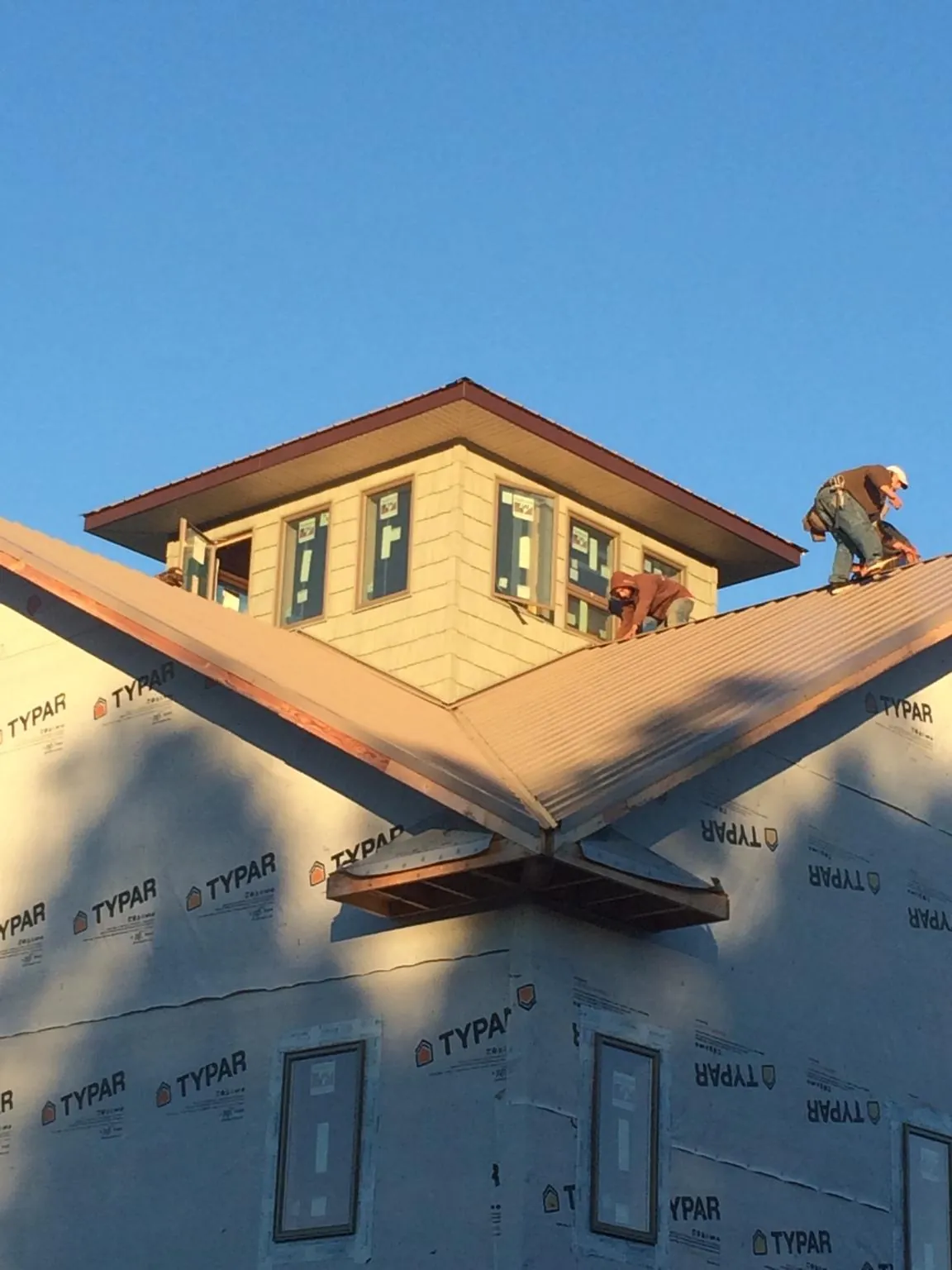 Roofers working around a rooftop cupola on a new metal roof at sunset — Roof Waterproofing in Halstead by Roofing Brothers